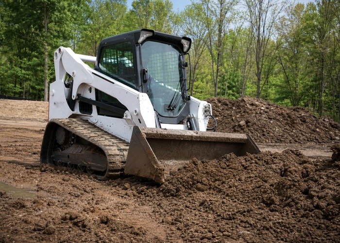 Compact track loader soft ground grading Compact track loader grading soft soil on a muddy site preparation area