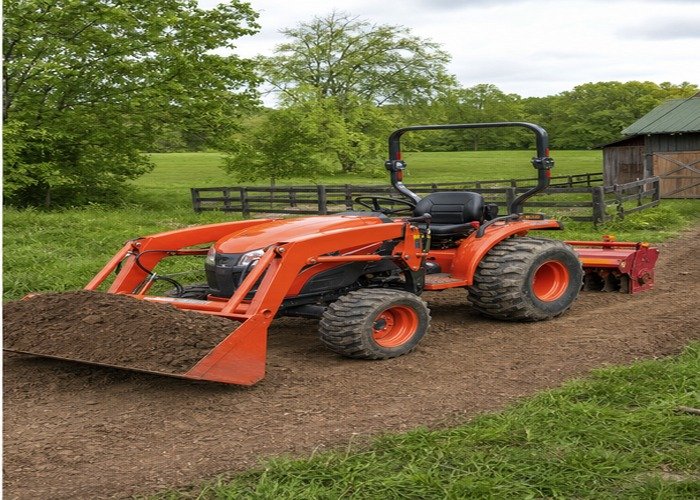 Compact tractor moving soil on a rural property as part of a small contractor equipment comparison