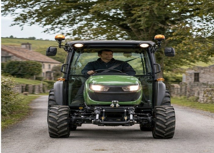 Compact tractor traveling slowly on a rural lane with lights on and safe operator posture