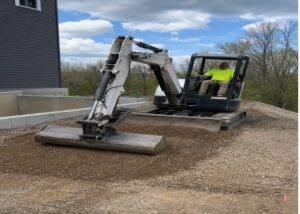 Mini excavator spreading a thin soil layer with a wide grading bucket