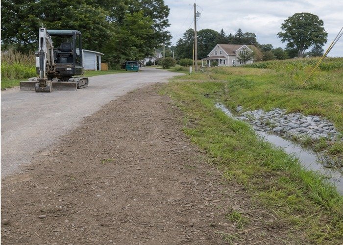 Finished graded trench corridor with drainage restored and excavator parked clear
