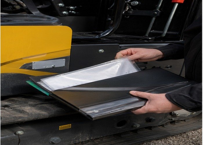 Buyer checking non-readable compliance and shipping documents beside a mini excavator Buyer checking non-readable compliance and shipping documents beside a mini excavator
