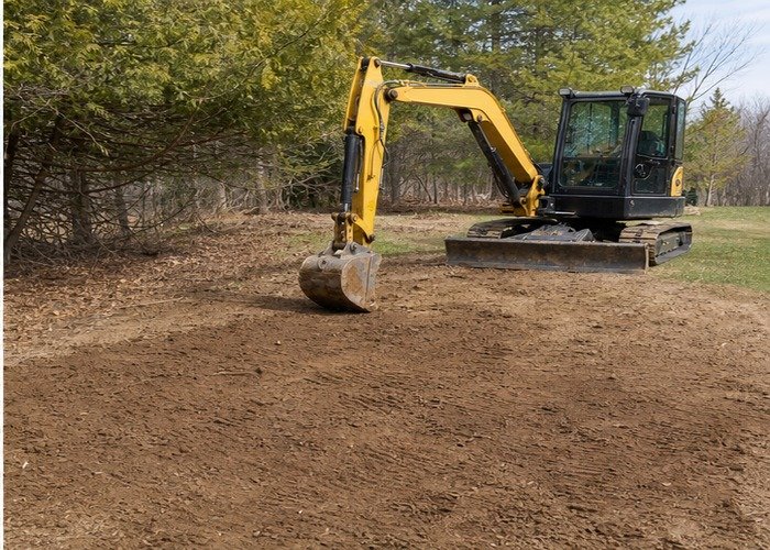 Mini excavator parked beside a graded and restored root barrier trench Mini excavator parked beside a graded and restored root barrier trench