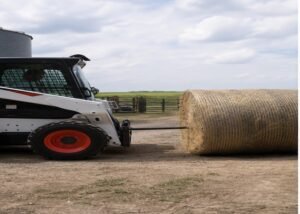 Skid steer aligning a bale spear with the center of a round bale