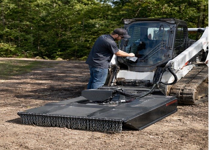 Skid steer with brush cutter attachment parked for hydraulic requirement checks
