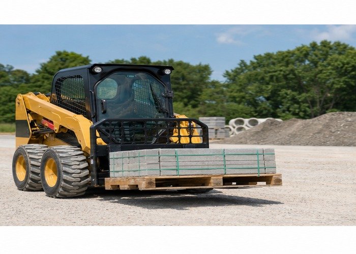 Skid steer carrying a low balanced pallet on a level gravel yard