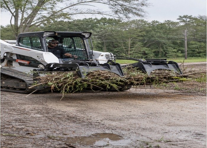 Skid steer carrying brush low and stable with grapple clamped Skid steer carrying brush low and stable with grapple clamped