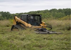 Enclosed-cab skid steer cutting overgrown pasture with a rotary brush cutter