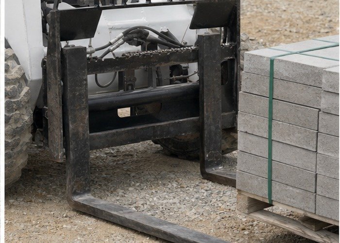 Operator checking skid steer fork spacing and load backrest before lifting Operator checking skid steer fork spacing and load backrest before lifting