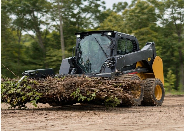Skid steer carrying brush low after a controlled hydraulic attachment test