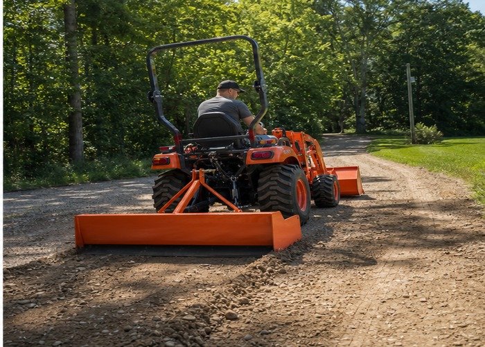 Compact tractor with box blade grading a gravel driveway Compact tractor with box blade grading a gravel driveway