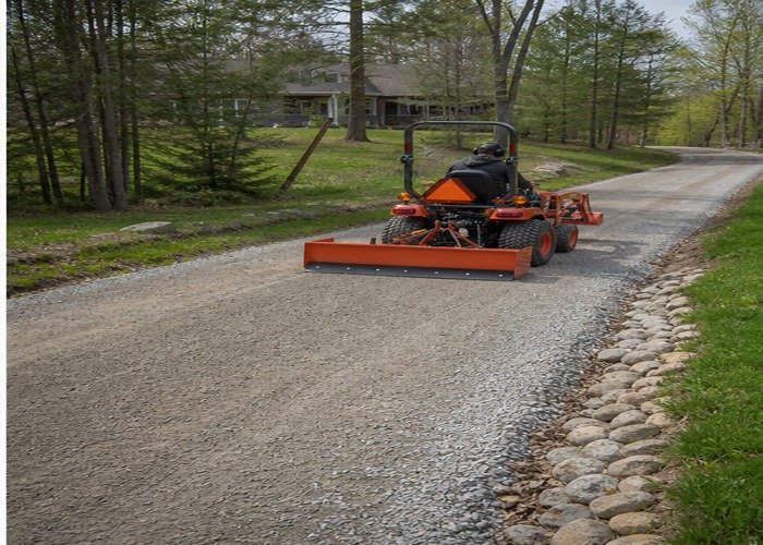 Compact tractor making a light finish pass on a smooth crowned gravel lane Compact tractor making a light finish pass on a smooth crowned gravel lane
