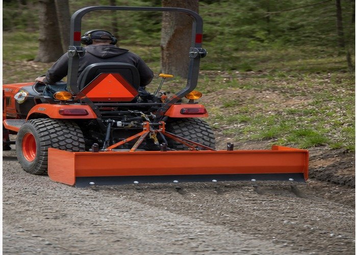 Box blade scarifier teeth loosening washboard gravel behind a compact tractor Box blade scarifier teeth loosening washboard gravel behind a compact tractor