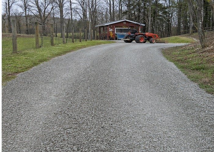 Smooth crowned gravel driveway with compact tractor parked at the end Smooth crowned gravel driveway with compact tractor parked at the end
