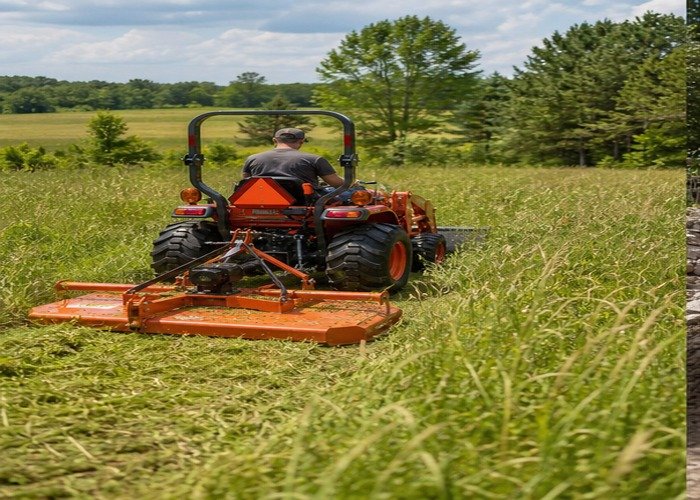 Compact tractor using a rotary cutter while mowing tall grass on a rural property