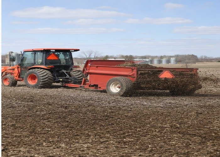 Compact tractor completing a calibrated manure spreading pass