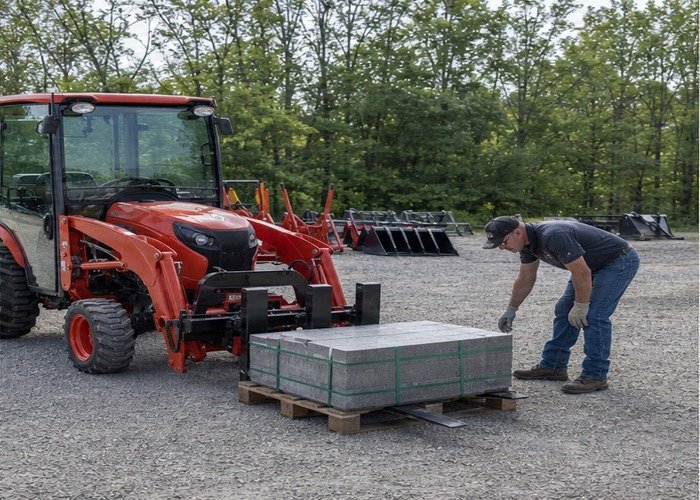 Operator checking fork spacing and pallet stability with the tractor stopped