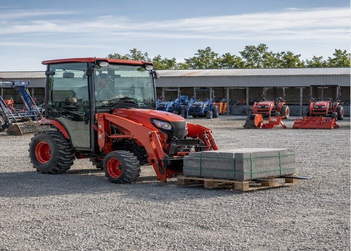 Compact tractor carrying a centered pallet low on correctly spaced forks