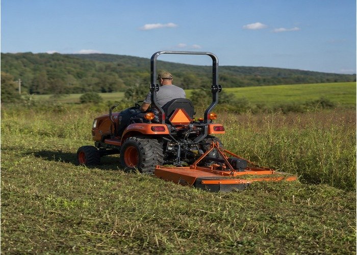 Compact tractor using a rotary cutter to mow tall field edges on acreage Compact tractor using a rotary cutter to mow tall field edges on acreage
