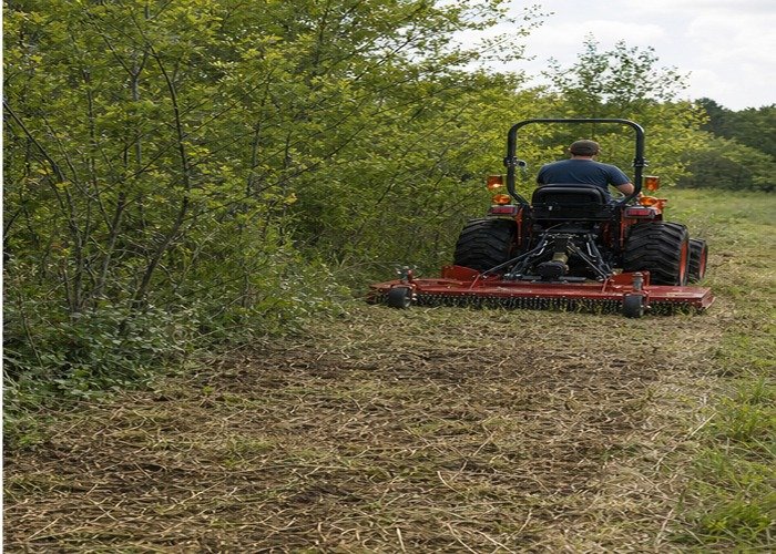 Compact tractor rotary cutter leaving a clean swath beside standing brush Compact tractor rotary cutter leaving a clean swath beside standing brush