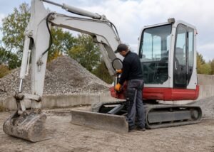 Technician greasing a mini excavator boom pivot
