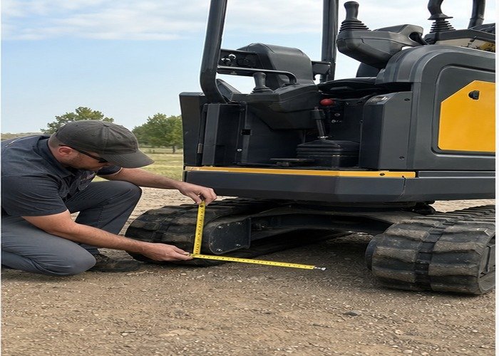 Technician measuring a grounded mini excavator rubber track Technician measuring a grounded mini excavator rubber track
