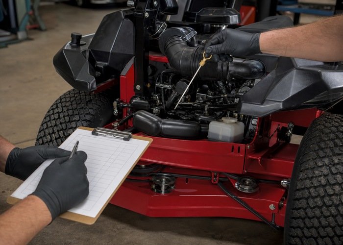 Technician recording preventive maintenance on a zero-turn mower
