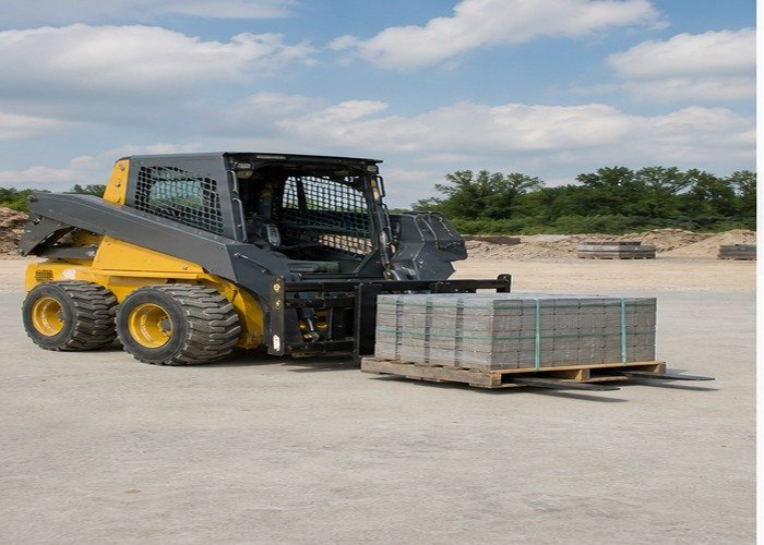Skid steer carrying a centered pallet low on level concrete