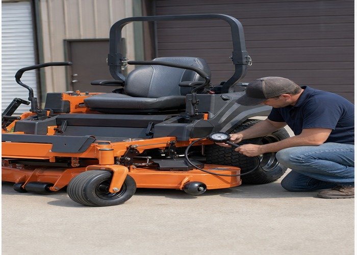 Operator checking cold tire pressure on a stopped zero-turn mower Operator checking cold tire pressure on a stopped zero-turn mower