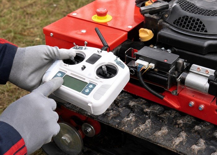 Technician pairing a remote mower transmitter with the receiver indicator visible