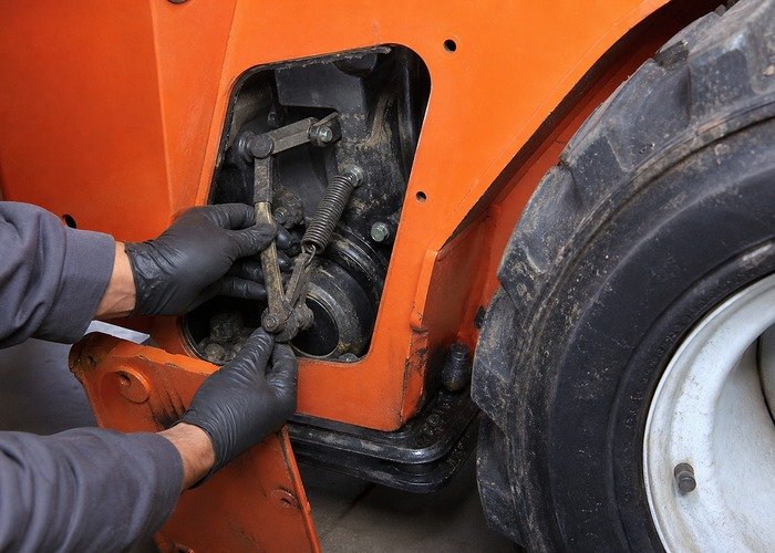 Inspecting skid steer parking brake linkage and return spring through a service opening