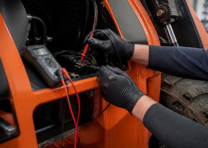 Testing a skid steer parking brake solenoid electrical connector with a multimeter