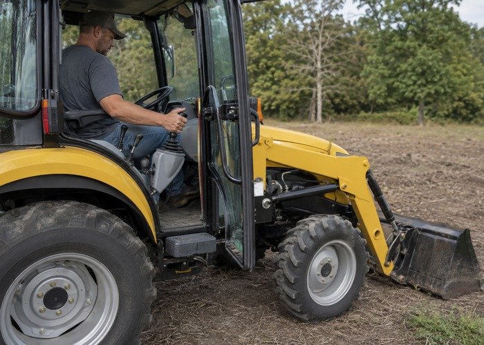 Operator moving the loader joystick with the tractor off and bucket lowered to relieve residual pressure