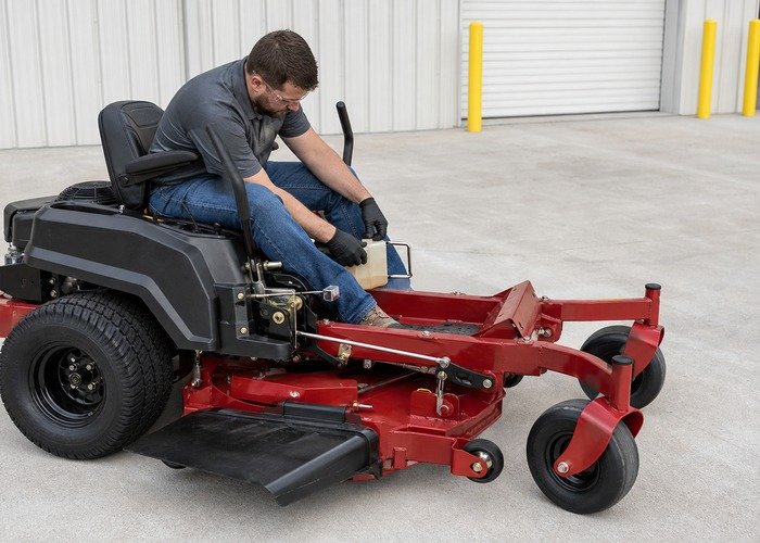 Technician checking zero turn mower hydrostatic drive reservoir and control linkage