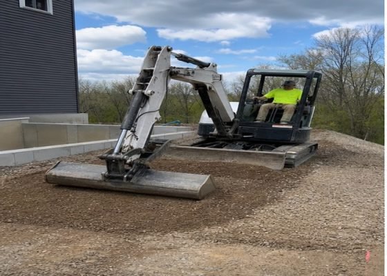Mini excavator spreading a thin soil layer with a wide grading bucket