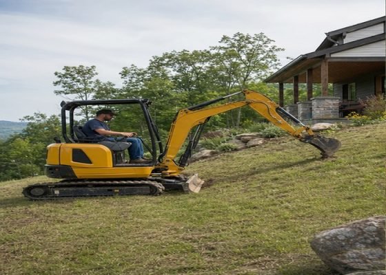 Mini excavator positioned carefully on a mild landscaped slope before digging