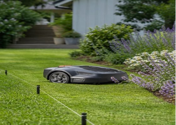 Robotic mower cutting a landscaped residential lawn near boundary markers