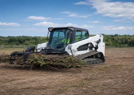 Skid steer carrying a modest brush bundle low in a root grapple