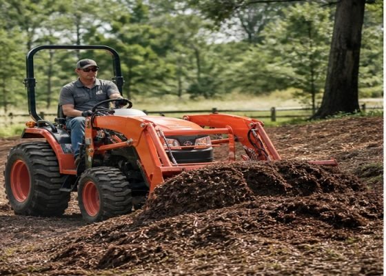 Compact tractor loader moving mulch with the bucket carried low