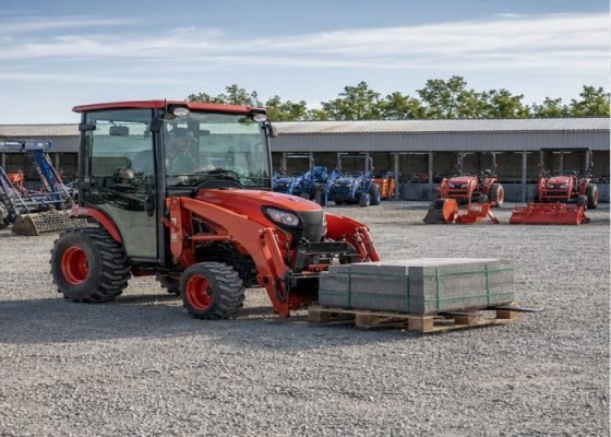 Compact tractor carrying a centered pallet low on correctly spaced forks