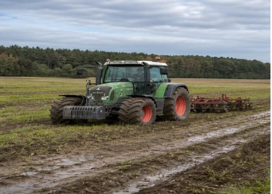 Farm tractor crossing a moist field on wide agricultural tires